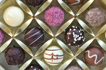 Assorted elegant chocolates in a gold container - full frame background, chocolate bon bons...