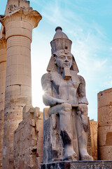 Seated statue of Ramesses II by the First pylon of the Luxor Temple, Egypt. Columns and statues of...