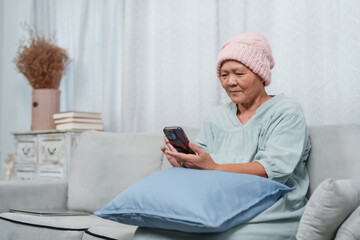 mother with cancer smiles as she engages with a smartphone, Joyful despite illness, a mother learns...