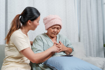 Concerned daughter comforts ailing mother, who is in distress, offering hand in soothing home...