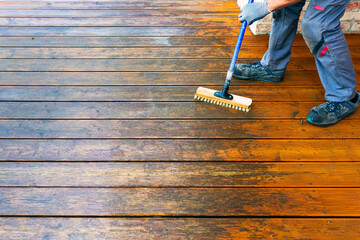 Terrace cleaning. Renovating a gray terrace using a hard scrub brush and green gel for renovating faded, gray boards - an alternative to washing with a high-pressure washer - obrazy, fototapety, plakaty