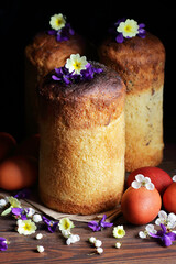 Homemade easter cakes with spring flowers and red eggs on dark moody rustic background, traditional...