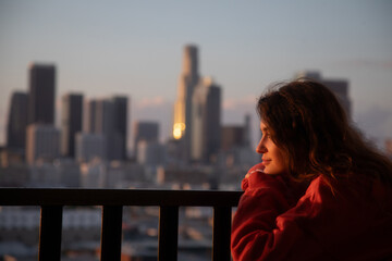Young pretty brunette woman enjoying life in front of downtown Los Angeles city in warm sunlight.