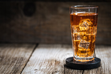 Ice tea with lot of ice in transparent glass on rustic wooden mood. 