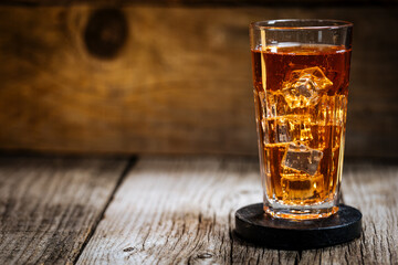 Ice tea with lot of ice in transparent glass on rustic wooden mood. 