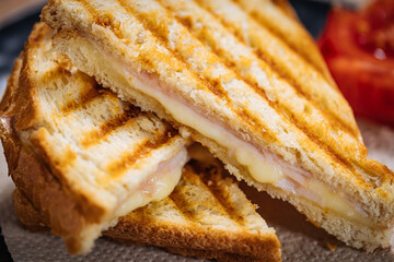 Toast sandwich with gouda cheese and turkey ham on a wooden background with ingredients in blurry...