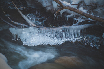 beautiful icicles and light in mountain creek at a winter day 