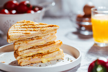 Toast sandwich with gouda cheese and turkey ham  on a bright background with ingredients in blurry background. Served with orange juice  and eggs