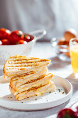 Toast sandwich with gouda cheese and turkey ham  on a bright background with ingredients in blurry background. Served with orange juice  and eggs