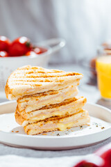 Toast sandwich with gouda cheese and turkey ham  on a bright background with ingredients in blurry background. Served with orange juice  and eggs