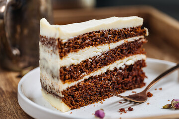 A piece of carrot cake served on rustic plate placed on bright sunny scene. Layered cake with cream...