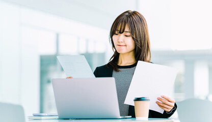書類を見て考えるビジネスウーマン