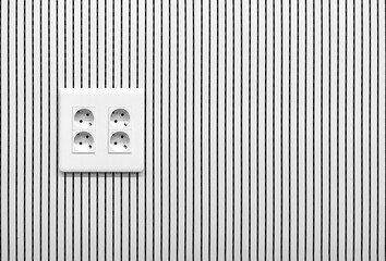 Enchufe cuádruple en una pared con líneas verticales, en blanco y negro con copy space