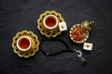 Muslim holiday concept - tea cups and Muslim rosary with a crescent moon