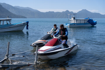 Young Hispanaic Men Lower Jet Skis from Trailer into the Water