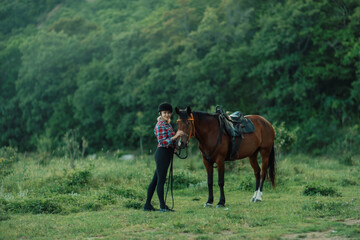 Fototapeta premium Happy blonde with horse in forest. Woman and a horse walking through the field during the day. Dressed in a plaid shirt and black leggings.