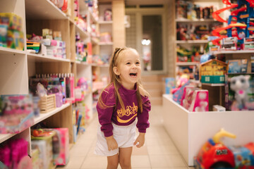 Adorable little girl shopping for toys. Cute female in toy store. Happy young girl selecting toy