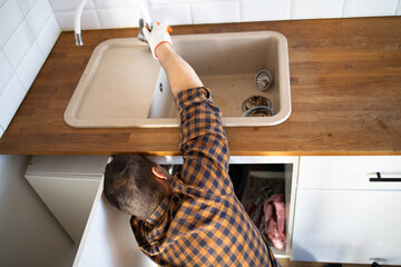 Plumber repairs plumbing pipes in kitchen sink. Removing blockage clog in drain pipe. Replacement...