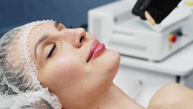 Laser hair removal, young woman's face. A cosmetologist applies ultrasound gel to a woman's face before epilation. A cosmetologist prepares a woman's skin for laser hair removal.