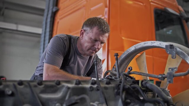 Auto mechanic performs maintenance on truck engine