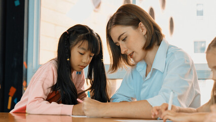 Panorama shot of happy diverse student and smart teacher drawing and coloring by using marker at...
