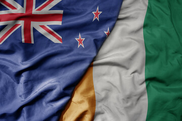 big waving national colorful flag of cote divoire and national flag of new zealand .