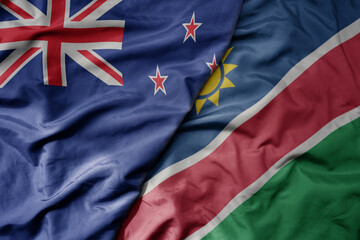 big waving national colorful flag of namibia and national flag of new zealand .