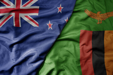 big waving national colorful flag of zambia and national flag of new zealand .