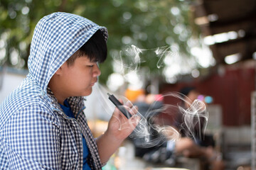 Asian preteen trying to smoke electronic cigarettes with friends in private area which hard to find...