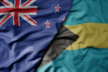 big waving national colorful flag of bahamas and national flag of new zealand .