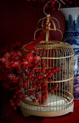 Wooden bird cage decorated faux by red flowers and fruits as Tet decoration