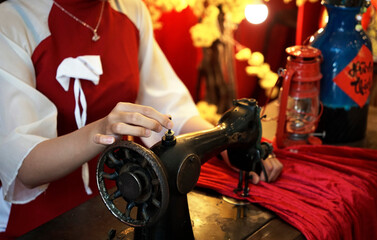 Fototapeta na wymiar Close up photo of Vietnamese lady’s hands, working on a sewing machine during Tet holiday