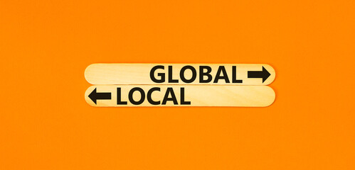 Global or local symbol. Concept word Global or Local on beautiful wooden stick. Beautiful orange table orange background. Business and global or local concept. Copy space.