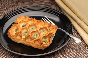 Spinich and cheese pastry on a black plate