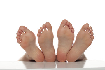 Two pairs od a beautiful well-groomed women's sole feet close-up on a white isolated studio background, The concept of foot skin care.