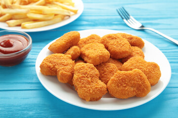 Homemade chicken nuggets and french fries with ketchup on blue wooden background.