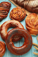 Bakery - various kinds of breadstuff. Bread rolls, bagel, sweet bun on blue background. Vertical photo