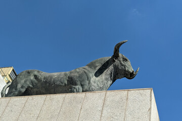 Statue of a bull against a blue sky on the facade of the building of bullring. The bull is an iconic symbol of Spain