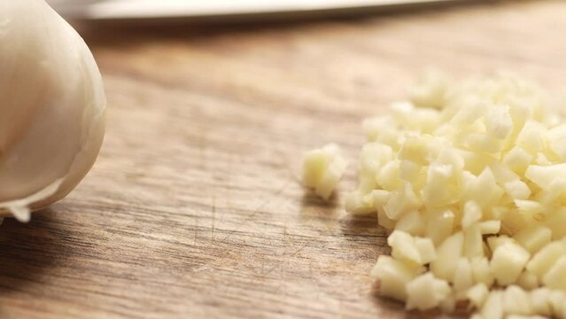 Chopping garlic with halves on a cutting board. Close-up, shallow dof.