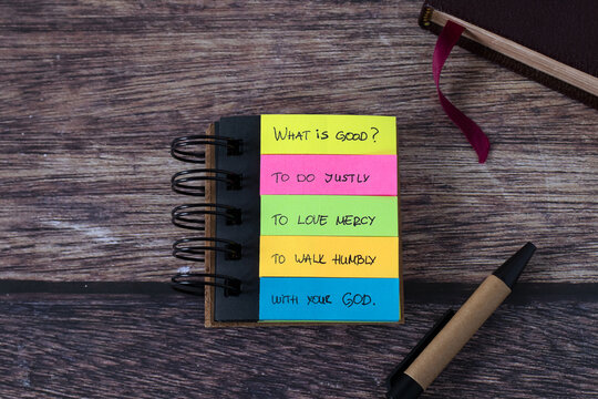 Christian justice, mercy, humility, and love for God Jesus Christ, handwritten text in a note with pen and holy bible book on wood. Prophet Micah 6:8 verse. Biblical concept.