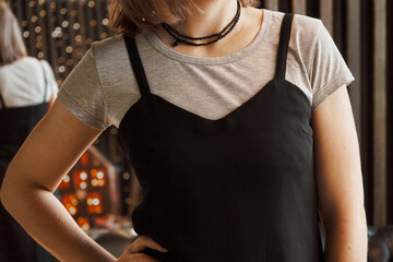 Woman wearing a black thin straps dress over a gray T-shirt. Concept: Combination of clothes from...