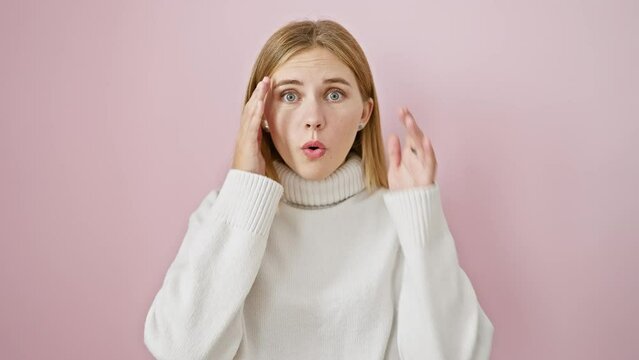 Gobsmacked blonde bombshell frozen in awe! shock and excitement painted across her beautiful face. fear, joy, amazement over a pink isolated background.