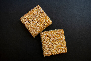 Til chikki on black textured background. Til chikki is an Indian sweets dishes made with jaggery and sesame. Indian festival makar sankranti special sweet.