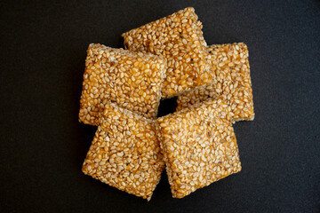 Til chikki on black textured background. Til chikki is an Indian sweets dishes made with jaggery and sesame. Indian festival makar sankranti special sweet.