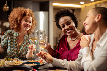 Women toasting with wine glasses at a dinner party