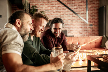 Group of men laughing and having drinks in a modern living room