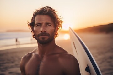 Portrait of a handsome young man with surfboard on the beach at sunset. Sport concept. Vacation and...