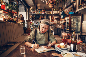 Senior waitress doing expenses at a restaurant table