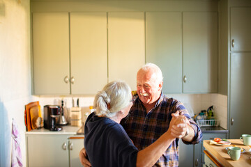 Happy senior couple dancing in the kitchen at home