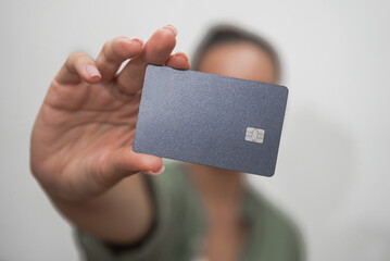 Woman customer shows credit card for making offline and online payments in store on blurred background in light studio modern technologies for shopping